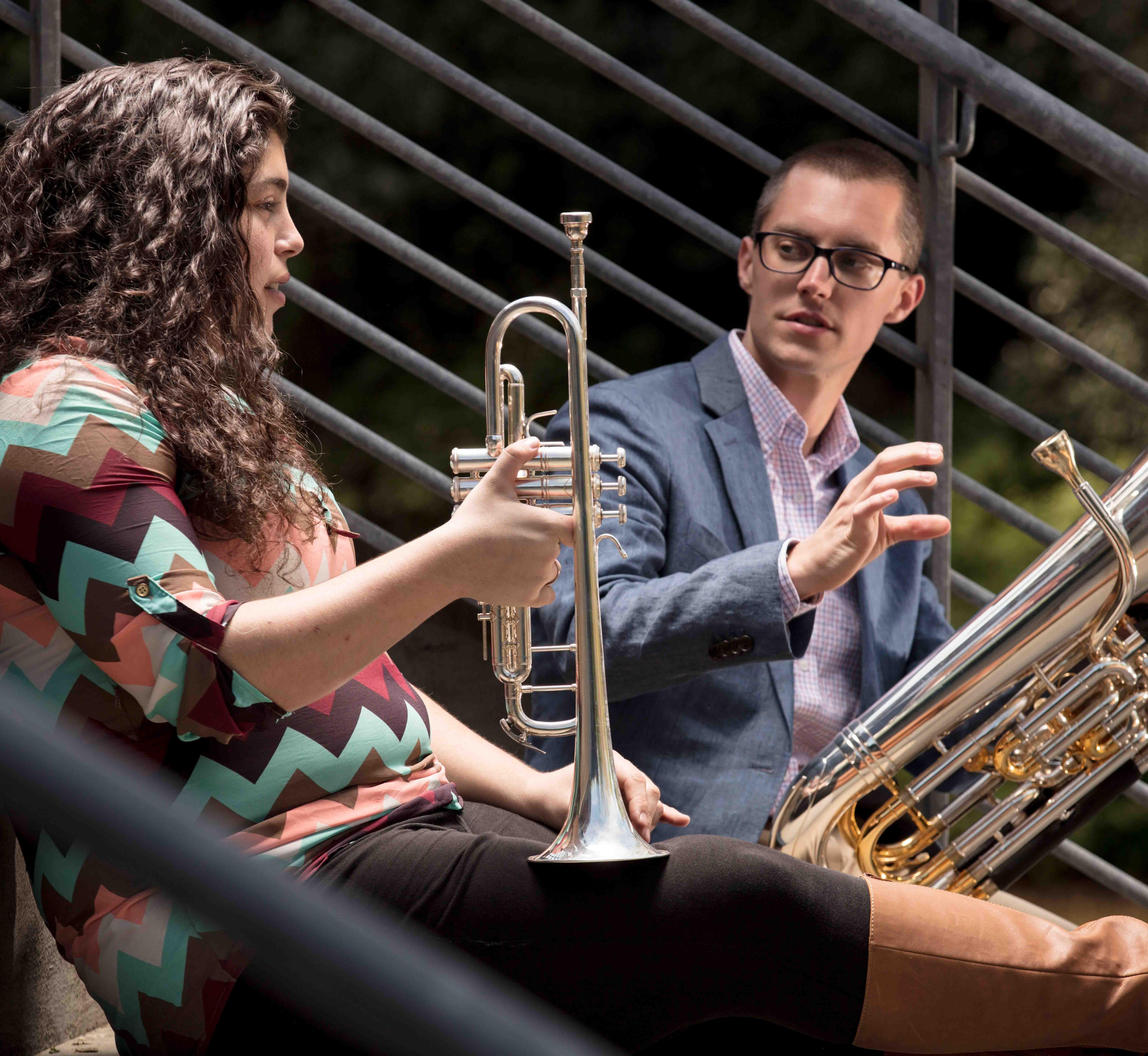 Two brass musicians sitting on the TLC stairs